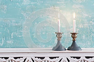 Two shabbat candlesticks with burning candles over wooden table