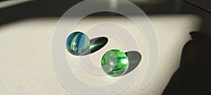 Two shadow marbles in a row green and blue