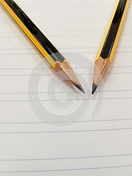 Two sharpened pencil over a ruled white paper