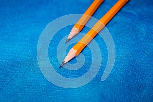 Two sharpened simple pencils lie on a blue background