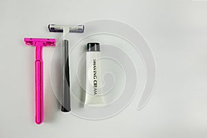 Two shaving sticks and white tube with shaving cream on light background with shadows. Pink for women and black for man. Family