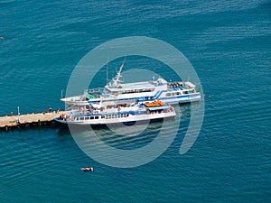 Two ships are moored near a small bay.