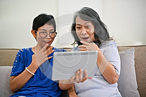 Two shocked and excited middle-aged women are watching something exciting online clips