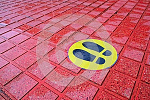 two shoe marks black on a yellow sticker marking of area and zone safety signs