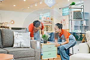 two shop assistants work together to move a small cabinet