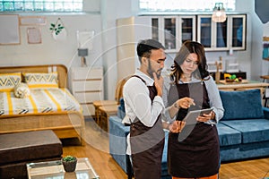 two shopkeepers with serious expressions while looking at a tablet