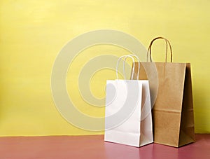 Two shoppin bags on the pink table against yellow wall.Empty space