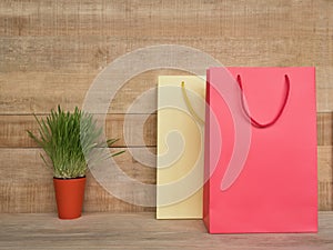 Two shopping bags on a wooden table. Green houseplant. Consumer concept