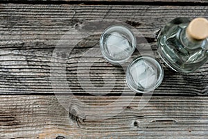 Two shot glasses with cold vodka or gin on wooden table,