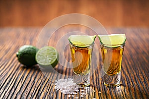 Two shot of gold tequila on a brown wooden background ,selectiv
