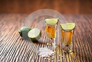 Two shot of gold tequila on a brown wooden background ,selectiv