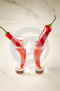 two shots of vodka and red chili pepper/rwo shots of vodka and red chili pepper on a white background