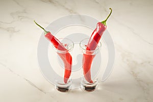 two shots of vodka and red pepper/two shot of vodka and red pepper on a white marble background. Selective focus