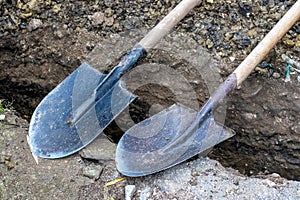 Two shovels lie near the dug trench