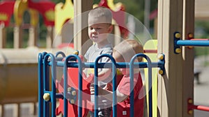 two sibling brothers playing together captain boat wheel playground sunny day