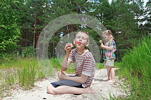 Two sibling children playing with soap bubbles on