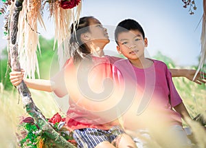 Two siblings children is swinging on a flower swing in a nature field for relaxation and childhood hapiness concept