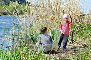 Two Siblings Holding Fishing Rods at the Riverside