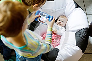 Two siblings kids boys taking picture with toy camera of cute baby girl.