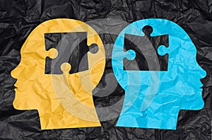 Two silhouettes of heads cut out from crumpled paper with puzzle pieces. Concept of similarity among people, finding a match