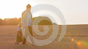 Two silhouettes outdoors in sunrise family father dad man farmer walking in wheat field with little child daughter girl