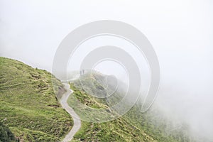 Two silhouettes walking on mountain path in fog