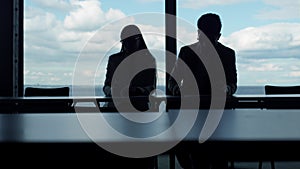 Two silhouettes working sea view in office. Business partners checking documents