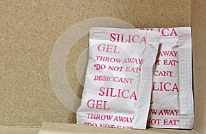 Two Silica gel packets in the bottom corner of a cardboard box.