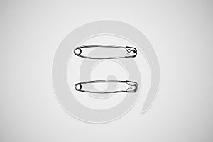 Two silver safety pins on white background