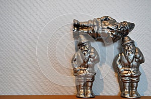 Two Silver Santa Claus figures hold up their best buddy Santa friend