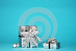 Two silver shiny boxes with a bow - New Year`s gift under a Christmas tree with blue background