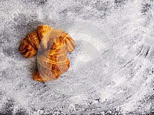 Two simple fresh homemade butter croissants isolated on white flour background.