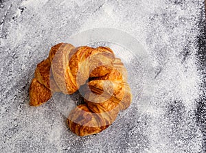 Two simple fresh homemade butter croissants  on white flour background.