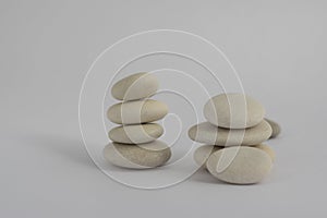 Two simplicity stones cairn isolated on white background, group of four and five white pebbles in tower