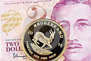 Two Singapore Dollar currency with a golden Krugerrand coin