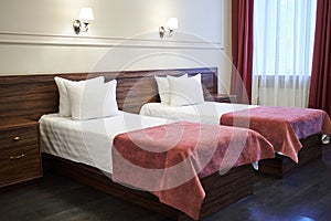 Two single beds with white linens are located in the bedrooms of the hotels, with space to copy