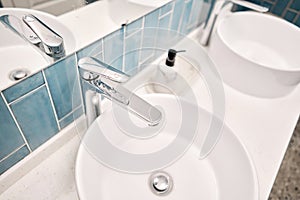 Two sinks in the bathroom sink next to stylish decorations. A beautiful sink with a metal faucet next to an mirror and a