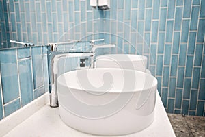 Two sinks in the bathroom sink next to stylish decorations. A beautiful sink with a metal faucet next to an mirror and a