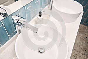 Two sinks in the bathroom sink next to stylish decorations. A beautiful sink with a metal faucet next to an mirror and a