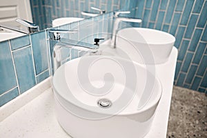 Two sinks in the bathroom sink next to stylish decorations. A beautiful sink with a metal faucet next to an mirror and a