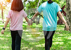 Two sister holding hands in the park in warm spring day. Happy friendship family concept