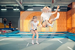 Mother and daughter jumping on trampoline and doing split