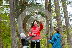 Two sisters and a brother in the park enjoy a warm spring day and have fun with a drone