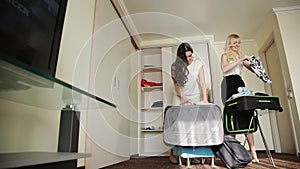 Two sisters collect things in a suitcase in a hotel room