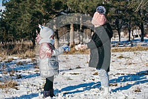 Two sisters of different ages on a winter walk in a snowy park