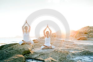 Two sisters are doing yoga exercises at the seashore of Mediterranean sea