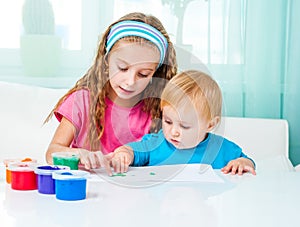 Two sisters draw finger paints