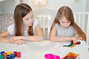 Two sisters drawing rainbow. stay at home. photo