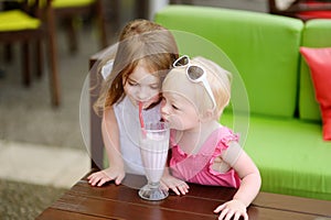 Two sisters drinking milkshake