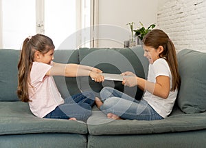 Two sisters fighting for laptop computer. Children and technology addiction